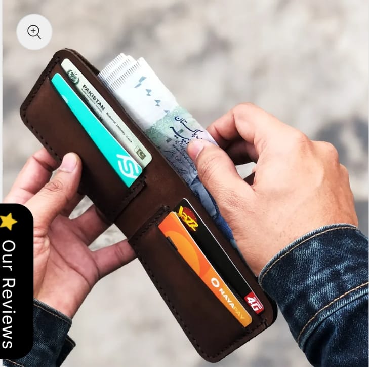 The Drifter Travel Wallet in espresso brown leather, closed, held in hand