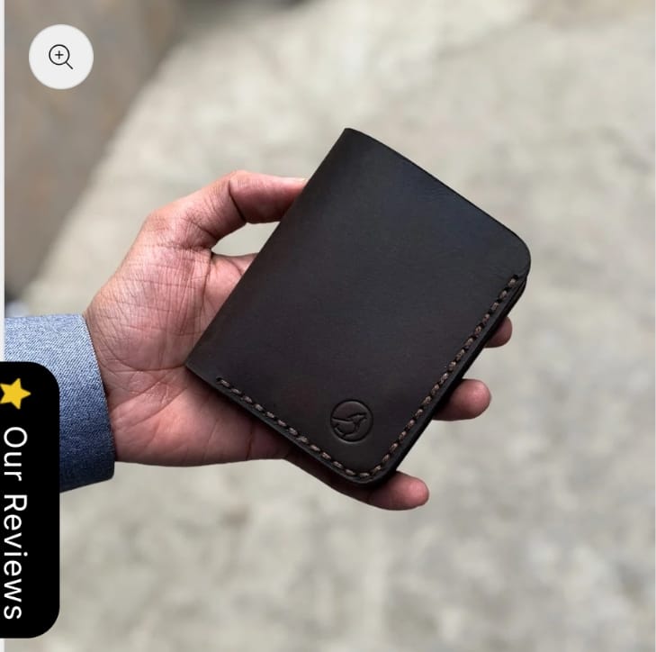 The Rancher Bifold Wallet in espresso brown leather, closed, held in hand